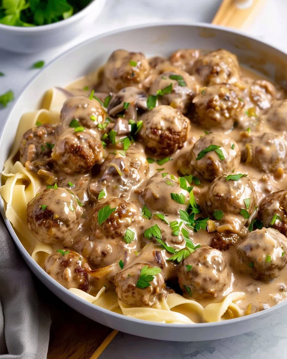 Creamy meatball stroganoff served with noodles and garnished with parsley